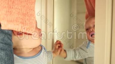 孩子哭着，同时看着镜子里的自己。 婴儿正在哭泣，站在母亲面前